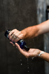 A deep cleaning beard wash by Badass Beard Care being transferred to a mans hands in shower