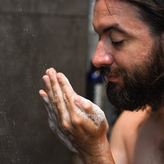 Man with facial hair in shower using invigorating Badass Beard Wash